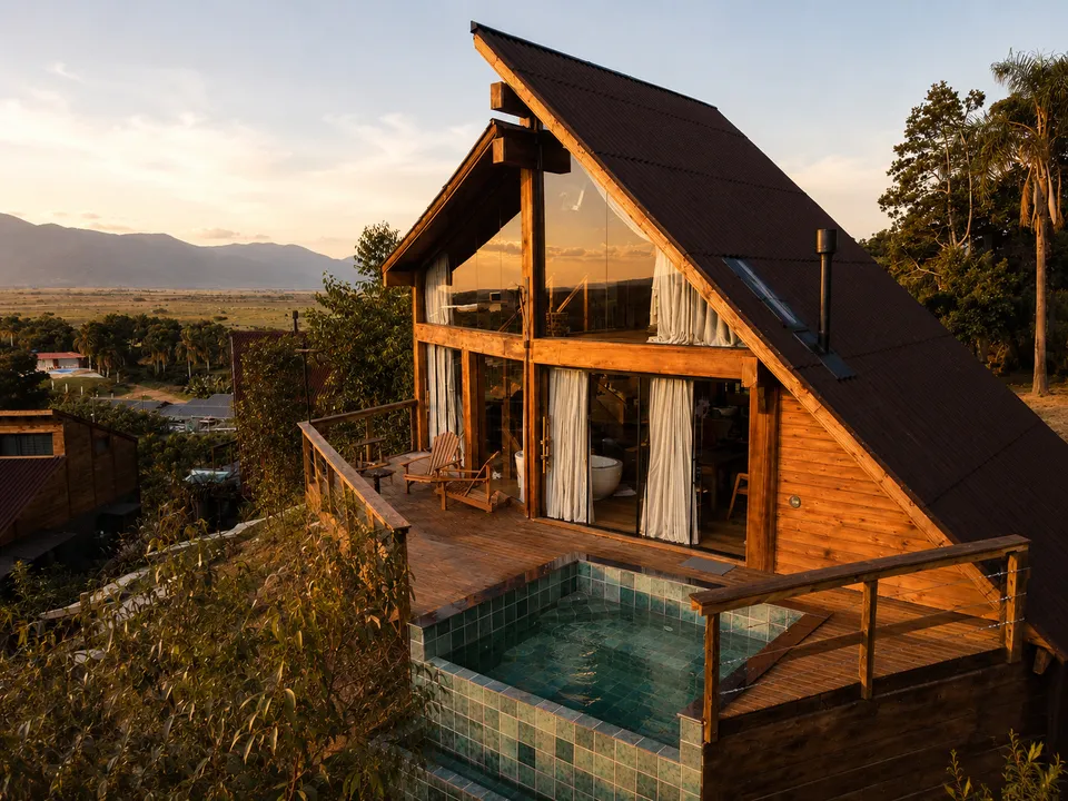 The A-frame façade of Cabana Acácia with its pool and the valley at sunset