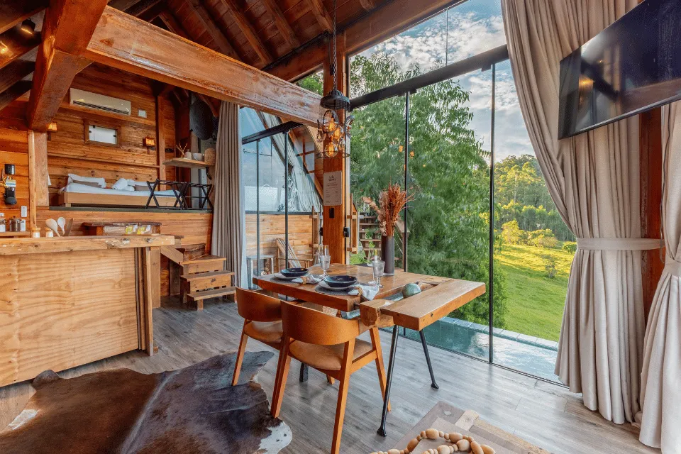 Wooden interior of Cabana Áurea with a table and windows onto the fields