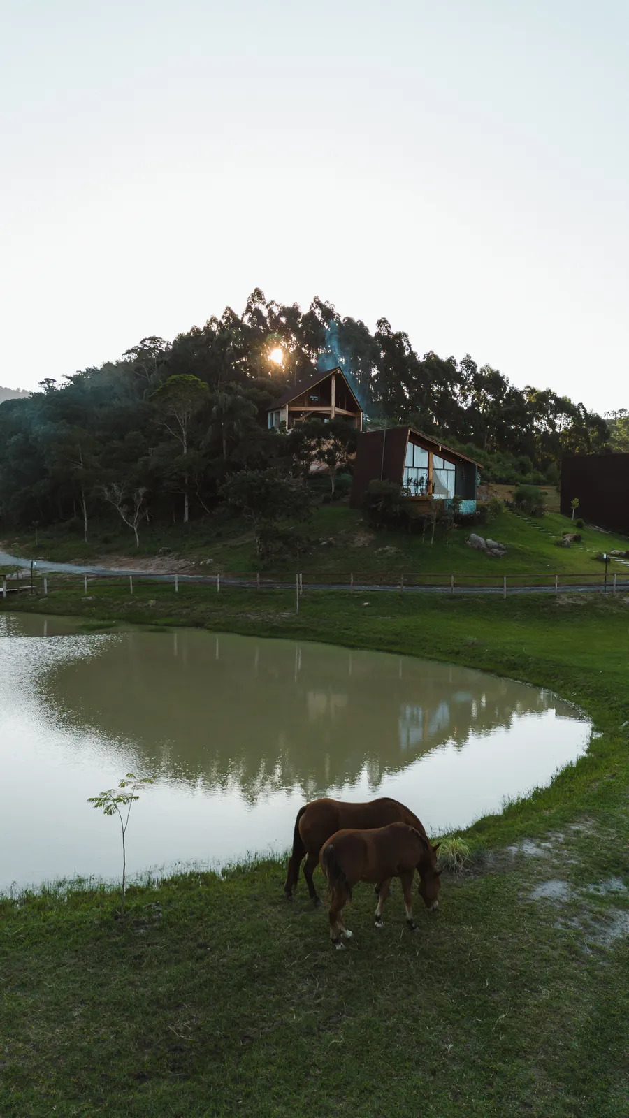 Lagoa com um cavalo pastando e as cabanas no alto do morro