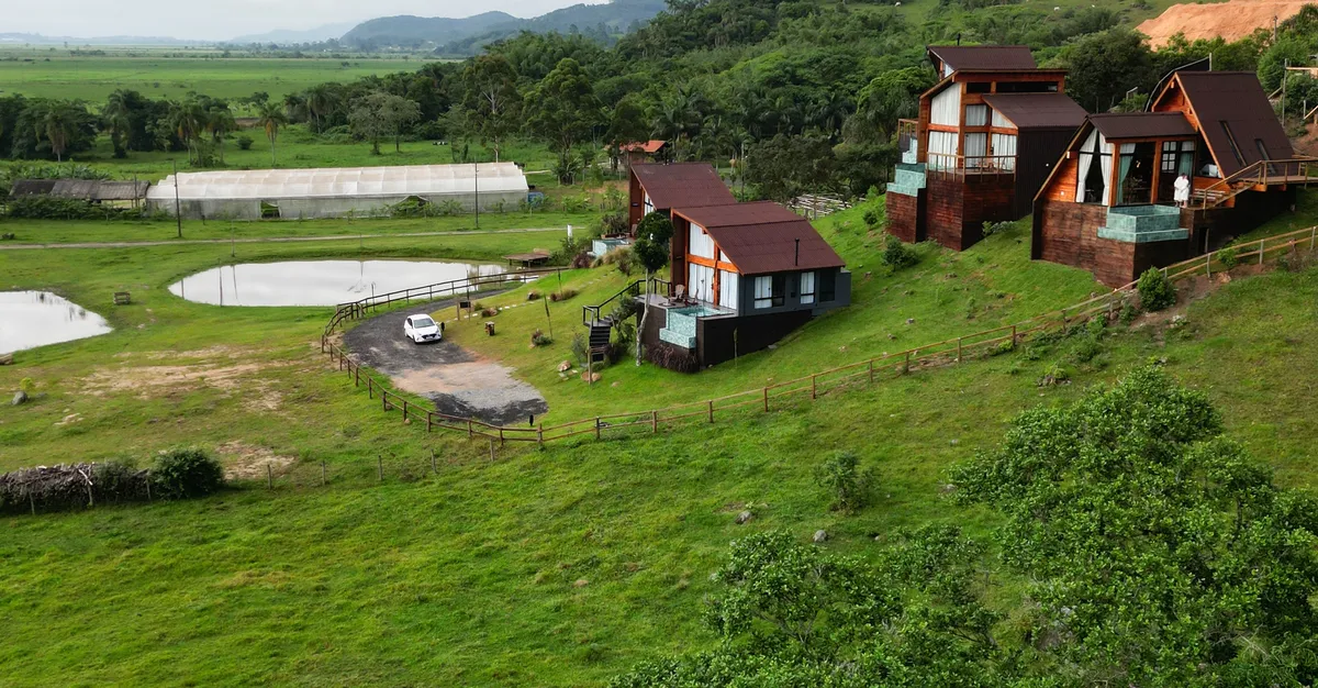 Vista do alto do vale com as cabanas, a lagoa e os campos